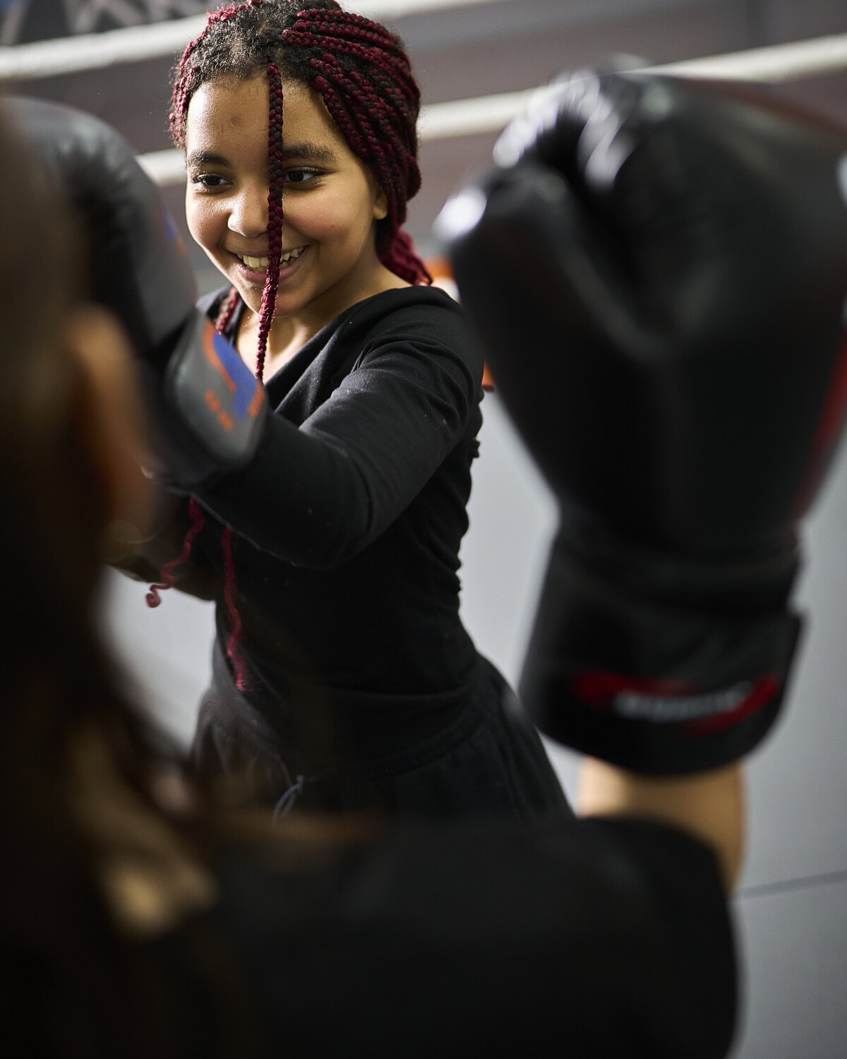 Ein Mädchen strahlt beim Training in der Sukhothai Academy und streckt den Boxhandschuh nach vorn