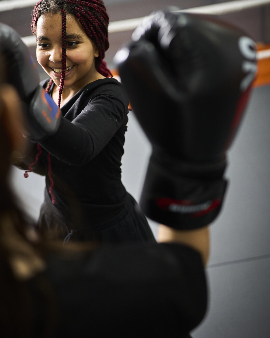 Ein Mädchen lächelt beim Training in der Sukhothai Academy, die Boxhandschuhe in Deckung